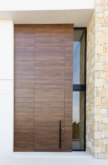 Puerta de entrada principal en madera y piedra en casa de diseño Cumbres | Chiralt Arquitectos Valencia