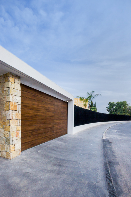 Puerta de garaje en madera y piedra en casa de diseño Cumbres | Chiralt Arquitectos Valencia