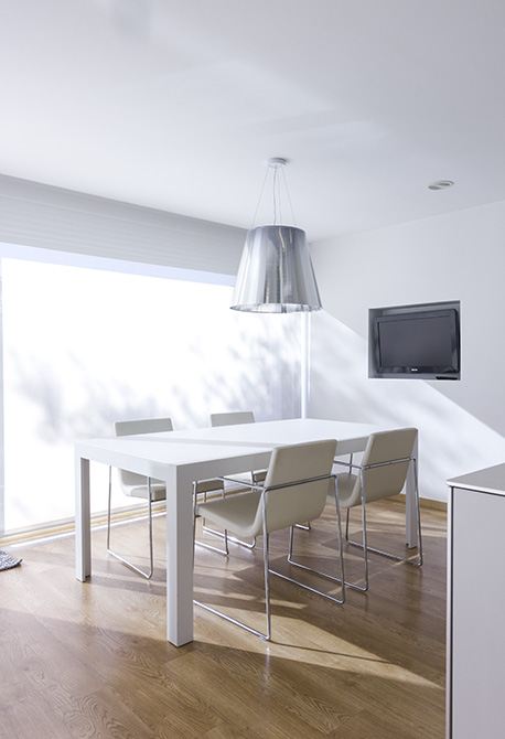 Mesa de cocina blanca y elegante con ventana al jardín y estor blanco.