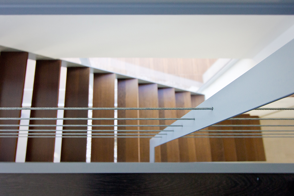 Escalera con peldaños de madera y barandilla de cables de acero en casa minimalista. Chiralt Arquitectos Valencia.