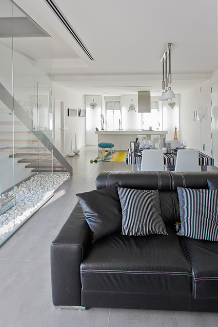 Salon comedor y cocina abierta en casa moderna con escalera de cristal y madera