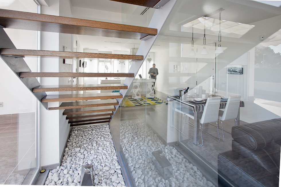 Escalera con peldaños de madera y barandilla de cristal en casa minimalista. Chiralt Arquitectos Valencia.