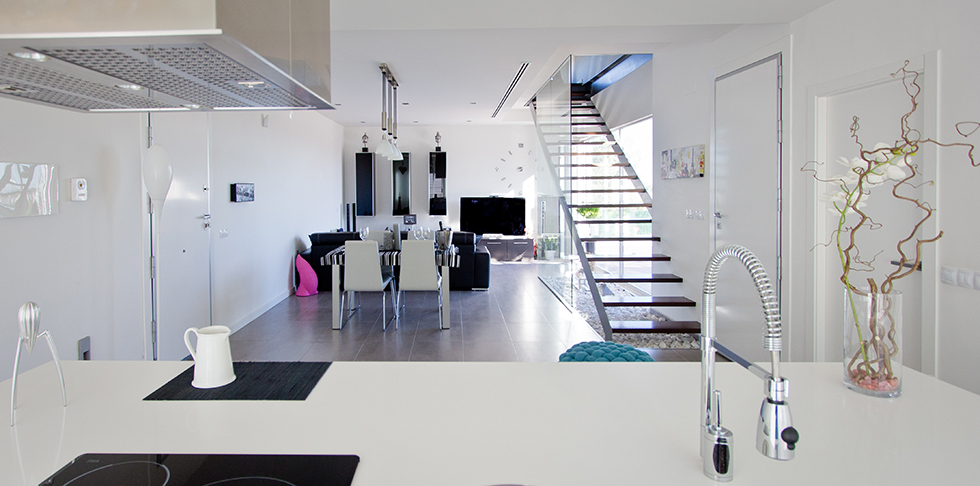 Escalera con barandilla de cristal en cocina salón de casa minimalista