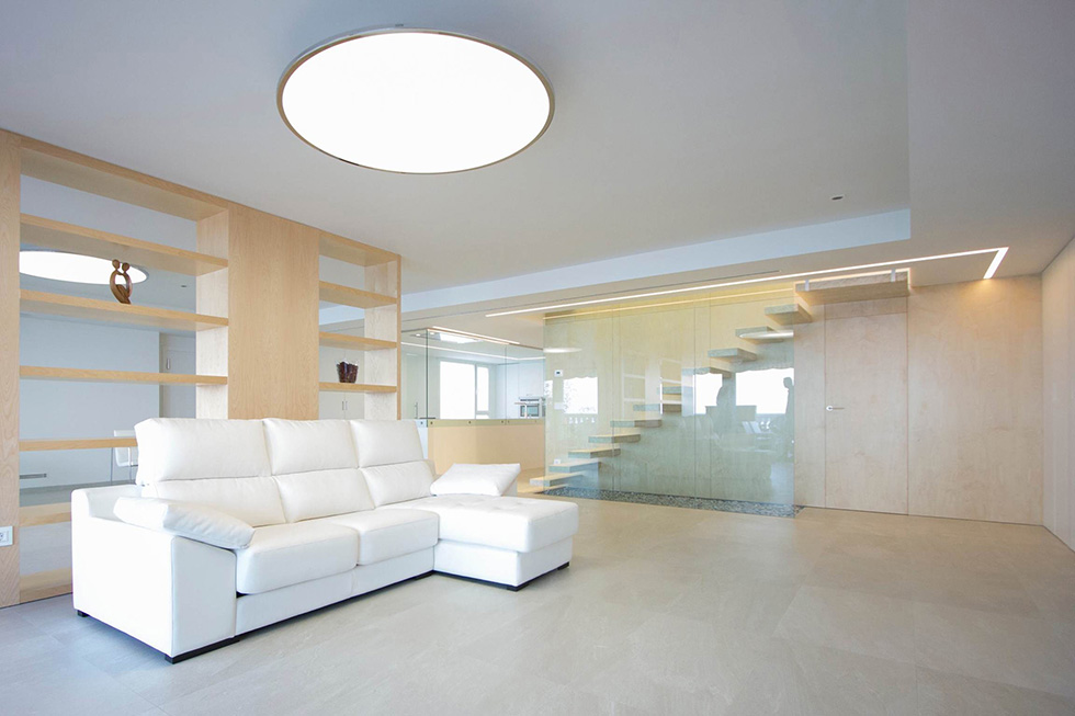 Salon minimalista en madera clara de haya con escalera de cristal