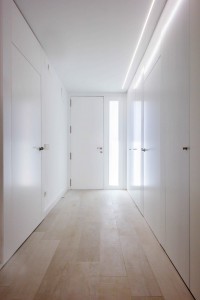 Recibidor con luz natural y armario blanco con puertas enrasadas minimalista low cost en reforma de casa. Chiralt Arquitectos Valencia.