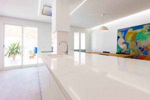 Isla en cocina blanca minimalista en reforma de casa. Chiralt Arquitectos Valencia.
