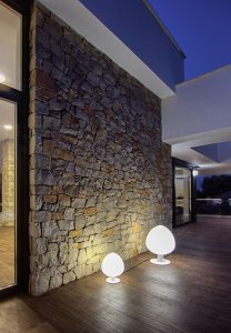 Foto de noche de pared de piedra en casa moderna con suelo de madera