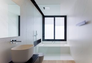 Baño de marmol blanco minimalista con lavabo en sobre encimera negra en casa de pueblo moderna Chiralt Arquitectos Valencia