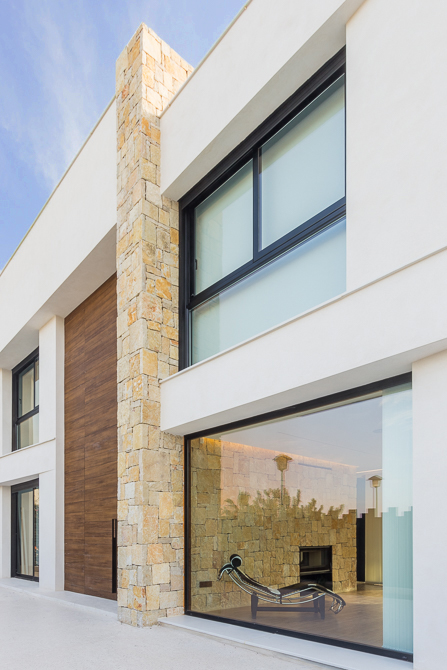 casa de diseño cumbres con fachada de piedra y gran ventanal de Chiralt Arquitectos Valencia