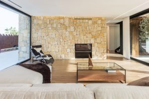 Salón con muro de piedra en casa de diseño Cumbres de Chiralt Arquitectos Valencia