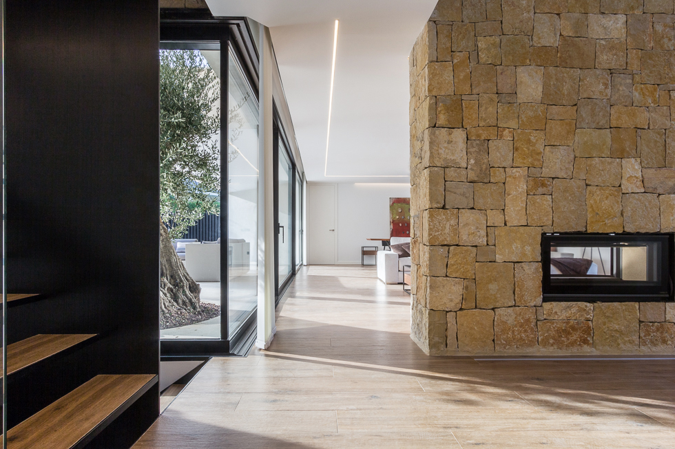 Pasillo con muro de piedra en casa de diseño Cumbres de Chiralt Arquitectos Valencia