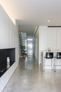 Salón con suelo hormigón armariada moderna blanca en vivienda estilo nórdico - Chiralt Arquitectos Valencia