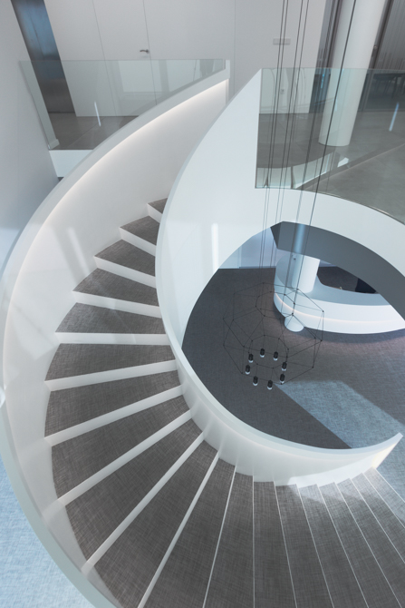Escalera blanca y gris en espiral en hall de oficinas modernas.