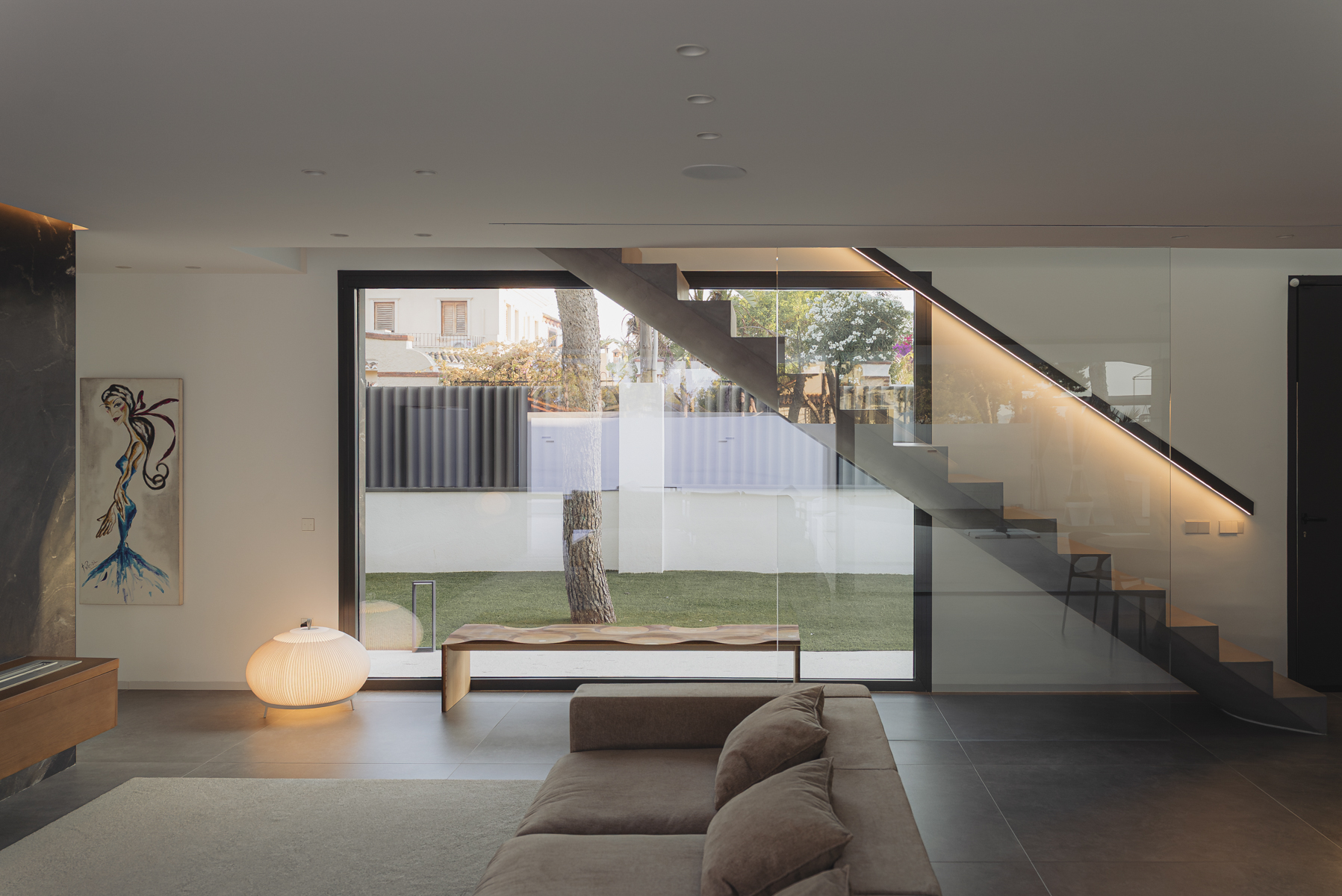 salón con escalera escultórica y gran ventanal en casa moderna en Valencia